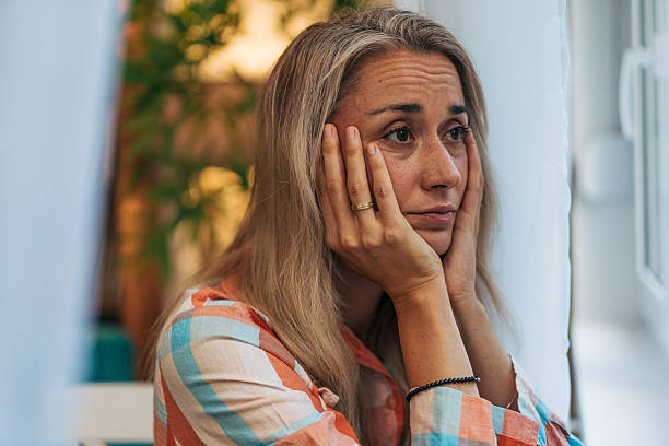 istock Sad woman holding her face in her hands looking away 2233556509