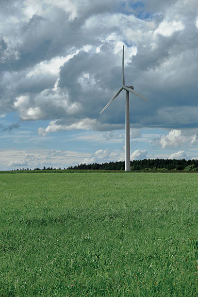 A windmill stands in a field against a cloudy sky.