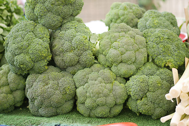 Broccoli heads arranged attractively at a vibrant farmer's market stand.