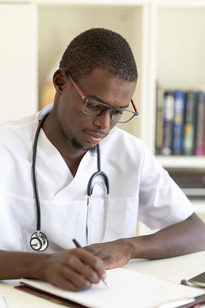 istock Young male doctor meticulously taking notes on a patient's chart in his office 2233563866
