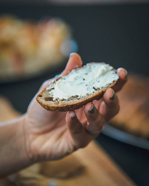 istock Hand holding rustic bread slice topped with creamy cheese spread in a close-up view 2233573832