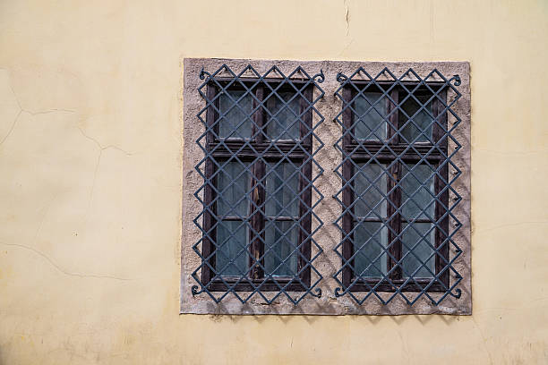 In Budapest, old yellow walls with diamond-patterned iron railings and stone-framed double windows. It combines security, symmetry, and architectural charm.