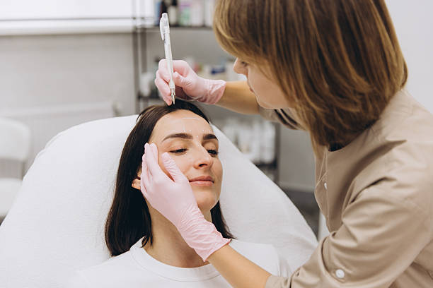 istock Cosmetologist drawing marks on woman's face before botox injections 2233579804
