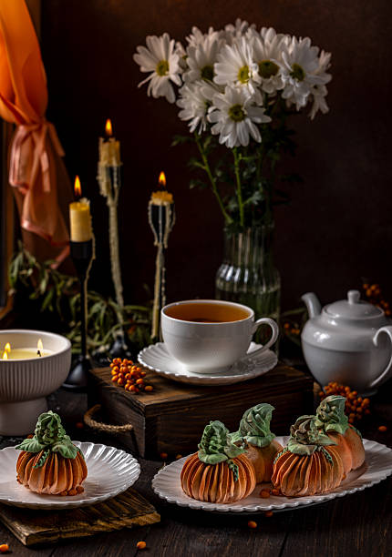istock Pumpkin shaped cakes with tea on a table decorated for autumn festivities 2233580445