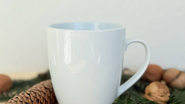 istock Close Up White Mug With Pine Cones and Walnuts on Evergreen Branches — Cozy Winter Decoration, Minimal Mockup with Copy Space for Banner, Branding and Template Design 2233580690