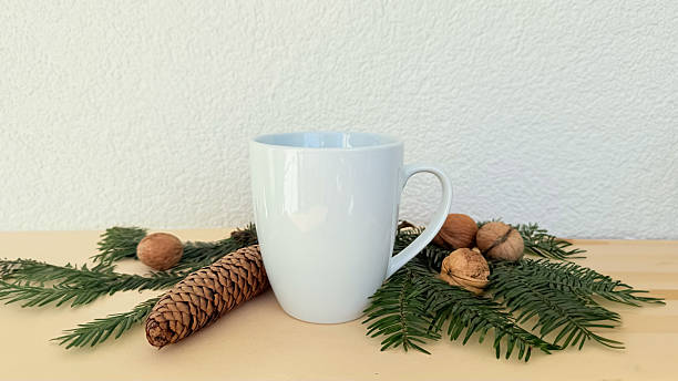 istock White Mug With Pine Cones And Walnuts On Evergreen Branches — Winter Decoration Mockup With Copy Space For Banner, Branding And Template Design 2233580695