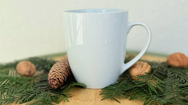 istock White Mug With Pine Cones And Walnuts On Evergreen Branches — Winter Decoration Mockup With Copy Space For Banner, Branding And Template Design 2233580697