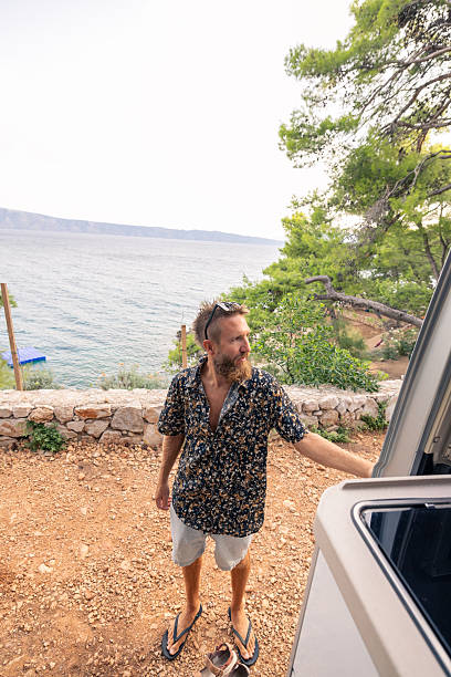 istock Man Enjoying Coastal View from Camper Van Door 2233583725