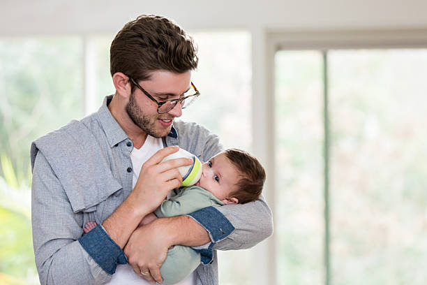 istock Happy Father Bottle Feeding His Infant Son at Home 2233586070