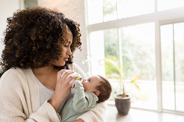 istock Mother bottle-feeding her baby in a bright home 2233586088