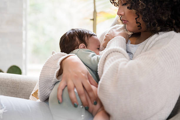 Mother lovingly breastfeeding her baby in a cozy home setting.