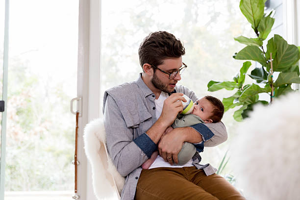 istock Father bottle-feeding his baby boy at home 2233586130