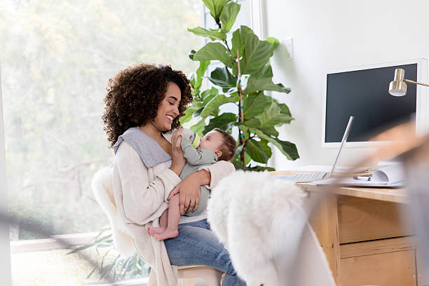 istock Happy mother feeding her baby while working from home 2233586139