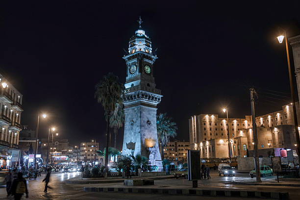 Dolmabahçe Clock Tower in Istanbul, featuring detailed Ottoman architecture, a large clock face, and a weather vane on top, set against a bright, overcast sky.