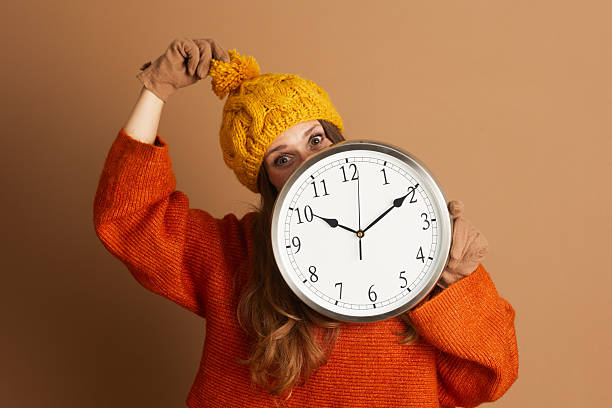 istock Playful Woman Peeks Over Wall Clock in Fall Attire 2233589640