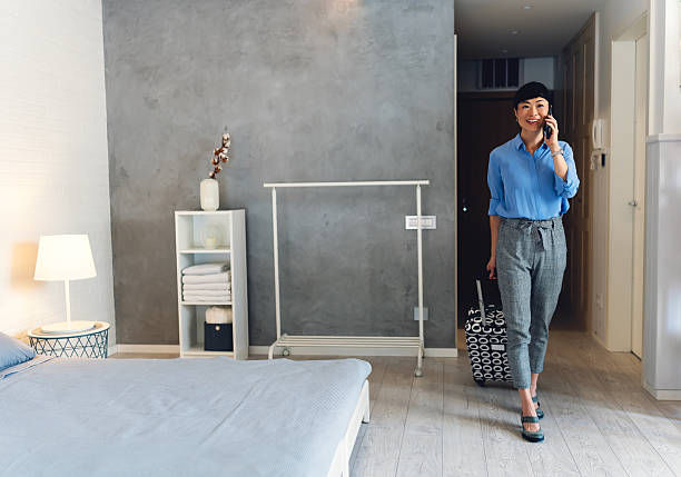 istock Young Asian traveler with suitcase talking on phone while entering modern hotel room, expressing happiness, diversity, and lifestyle of tourism and business travel 2233591281