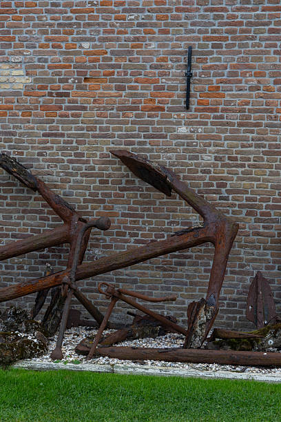 Rusty metal sculptures leaning against a textured brick wall, showcasing artistic design and industrial elements in an outdoor setting