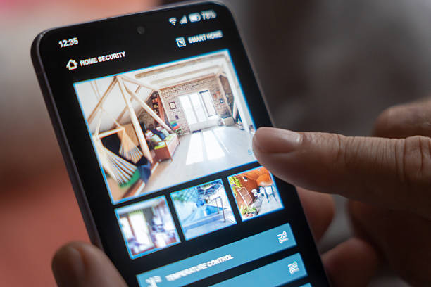 istock Man's hand holding a mobile phone with smart home control app 2233592654