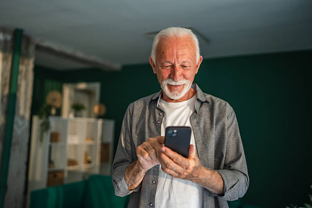 istock Senior man using smart phone and smiling at home 2233593016