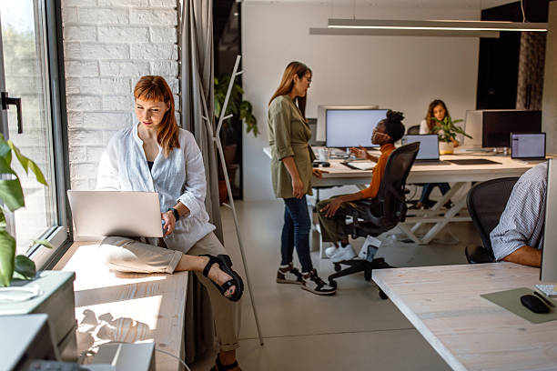 istock Young female white collar worker using laptop while siting by the window in the modern office 2233593059