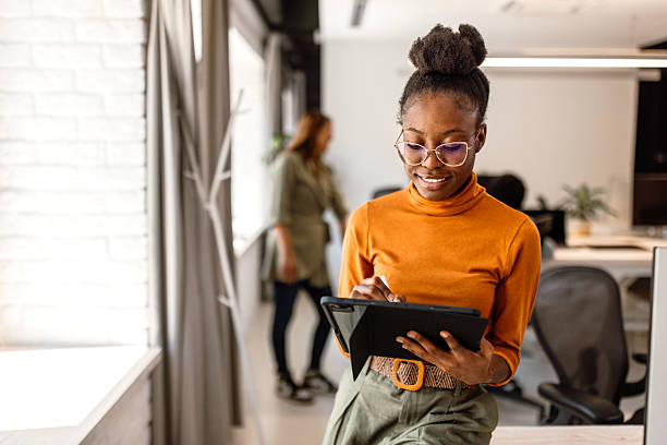 istock Young beautiful black woman working using digital tablet in the modern office 2233593131