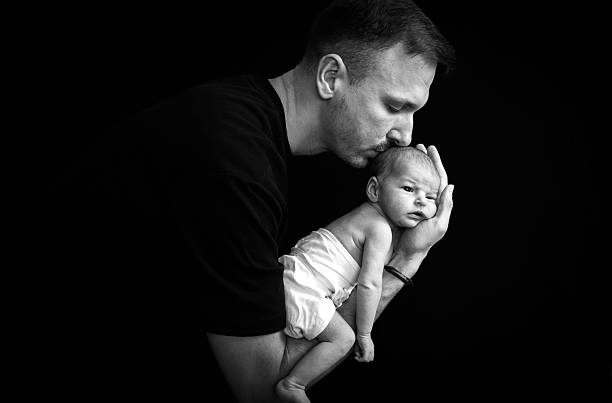 istock Newborn baby sleeping in her father's arms 2233595798