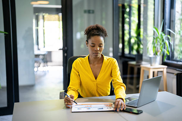 istock Focused businesswoman analyzing charts and reports in modern office 2233601137
