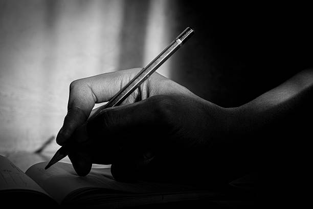 istock Close Up of Hand Writing with Pencil on Notebook 2233603795