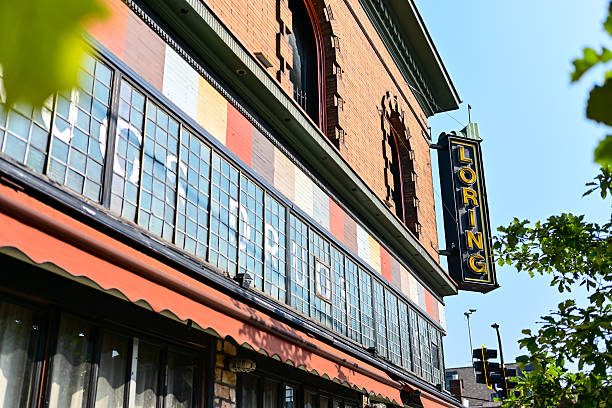 Minneapolis, Minnesota, USA - August 2nd, 2025. A building that has went through many rebrands sits empty. LORING sign and DRUGS DRUGS DRUGS stained glass remain intake.