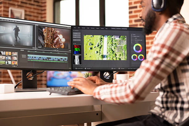 Videographer with headphones edits cinematic content, syncing audio with footage, applying color grading and transitions. Post production coordinator reviewing film montage in home studio with music.