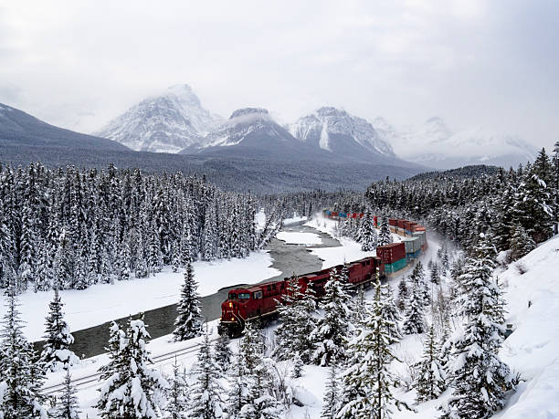 istock Long Red Freight Train Passing Through a Stunning Snowy Mountain Landscape 2233608498