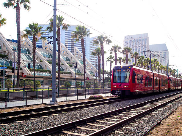 istock Modern Urban Red Tram Passing Through Cityscape with Palm Trees Behind 2233608569