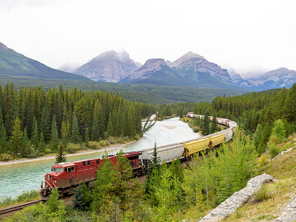 istock Freight Train Traveling Through Scenic Mountain Valley with River and Forest 2233608697