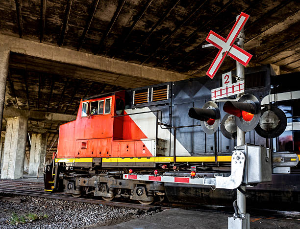 istock Red Train Locomotive Passing Under Bridge with Railway Crossing Sign 2233608748