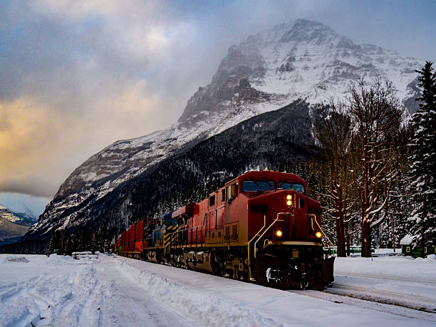 istock Red Freight Train Traversing Snowy Mountain Valley During Sunset 2233608827