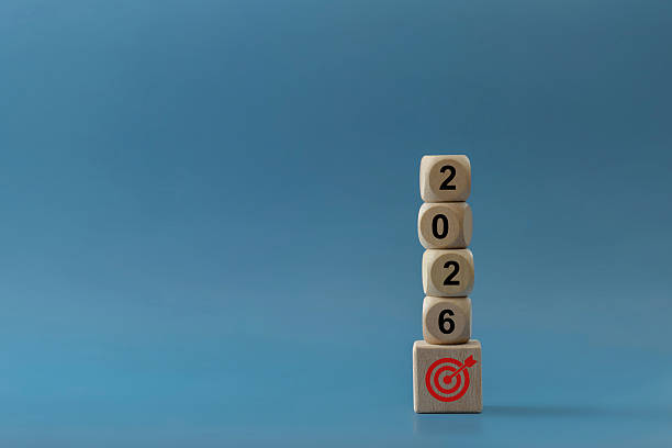 istock Wooden blocks stacked to form 2026 stand on a base cube with a red target icon against a clean blue background, symbolizing goal setting, planning, strategy, business vision and new year's success. 2233610940