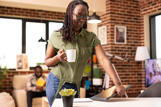 istock Self employed woman standing with coffee and laptop 2233614086