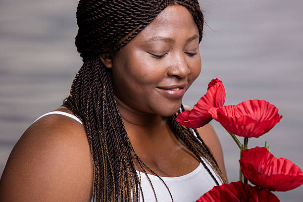 Portrait of a beautiful young black woman with long black hair holding a flower basket, studio shot in front of a white background