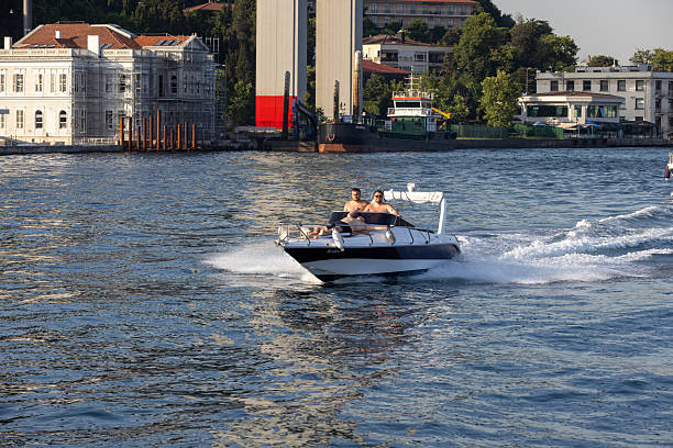 Bosphorus Strait, Istanbul / Turkey - September 29 2019: Power boat taxi in Bosphorus Strait moving fast and splashing water. Anatolian Site of Istanbul and Bosphorus Bridge in the background.