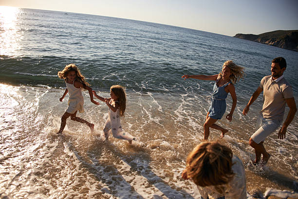 A family run down a tropical paradise beach during sunrise.