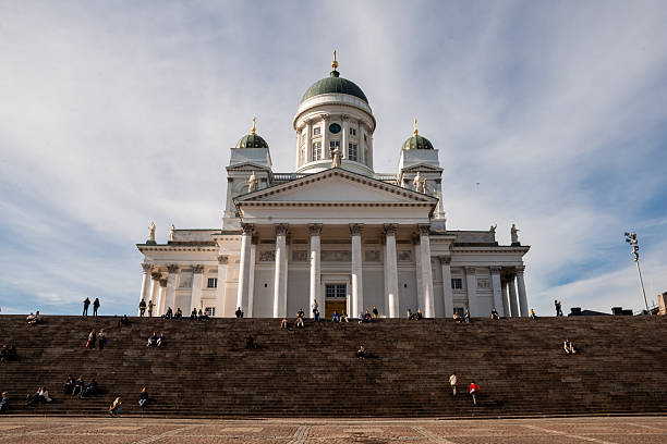 Helsinki, Finland - June 21, 2015 - Majestic helsinki cathedral with visitors on stairs under blue sky.
