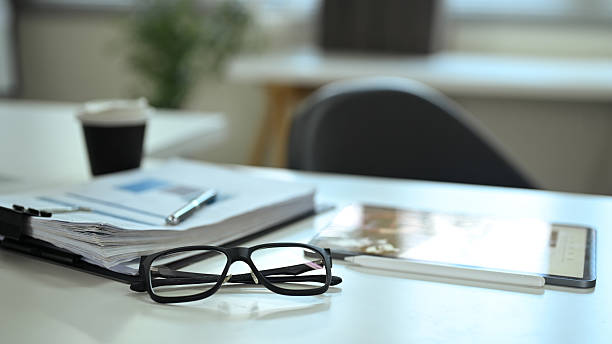 istock Close up of office desk with eyeglasses, documents, and coffee cup 2233619121