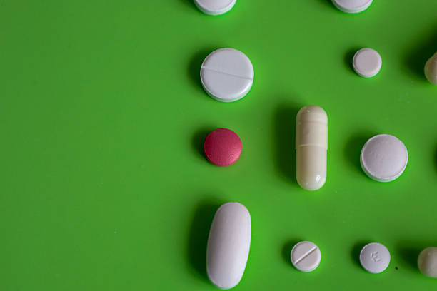 istock Randomly arranged colorful pills and capsules on a bright green background. This macro shot emphasizes the texture and shape of the medications. 2233619769
