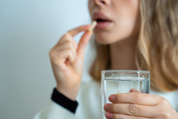 istock Woman drinking water with pill 2233619938