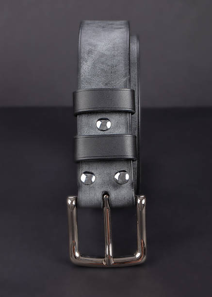 Black leather belt with metal buckles on a dark gray background.