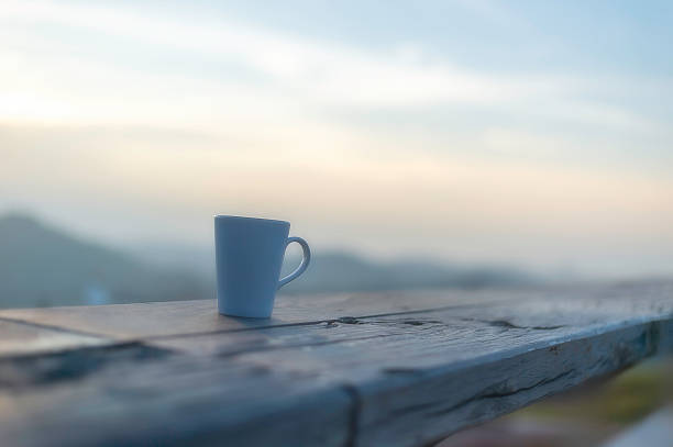 Cup of coffee on wooden table at sunset, sunset nature background nature concept.