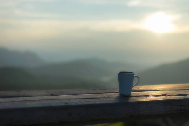 Cup of coffee on wooden table at sunset, sunset nature background nature concept.