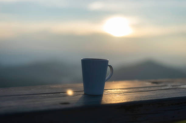 Cup of coffee on wooden table at sunset, sunset nature background nature concept.