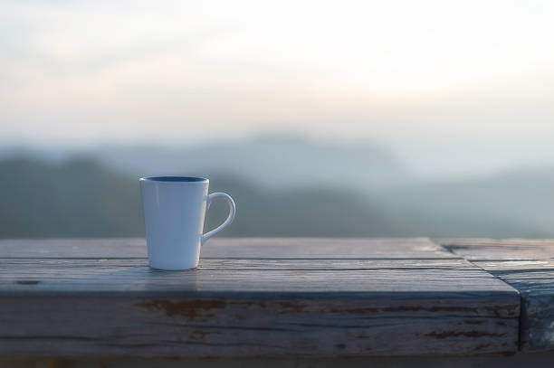 Cup of coffee on wooden table at sunset, sunset nature background nature concept.