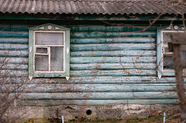 old wooden building with a roof made of asbestos tiles. old abandoned house made of wood and a poisonous asbestos roof. ruin. broken window panes.